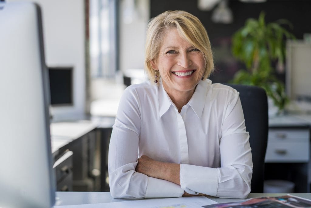 Happy mature businesswoman sitting at desk